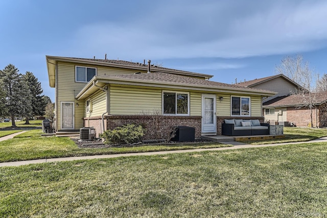view of front facade featuring an outdoor living space, brick siding, central AC unit, and a front yard