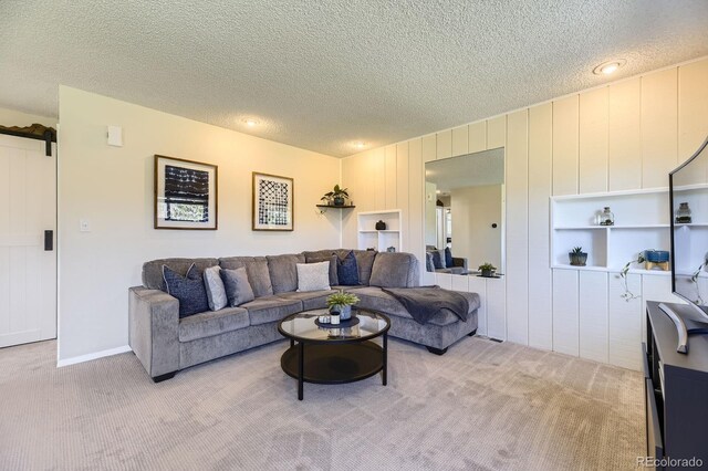 living area featuring light colored carpet and a textured ceiling