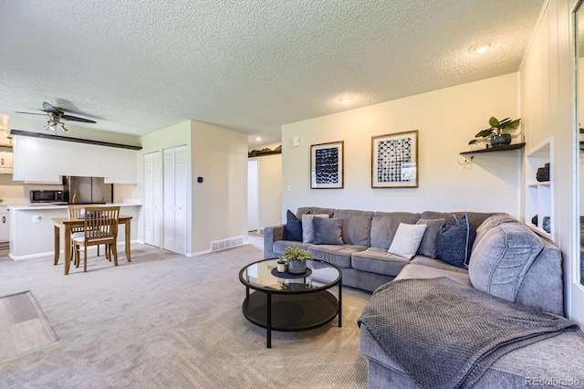 living area featuring visible vents, baseboards, a ceiling fan, and light carpet