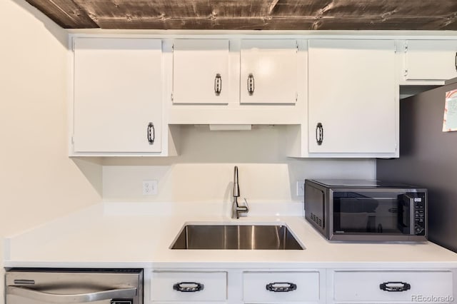kitchen with dishwashing machine, black microwave, white cabinetry, light countertops, and a sink
