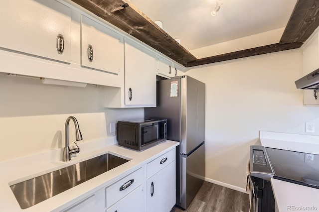 kitchen with black microwave, dark wood-style floors, light countertops, white cabinets, and a sink