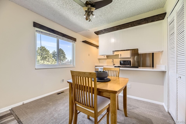 dining area with baseboards, carpet flooring, a textured ceiling, a ceiling fan, and visible vents