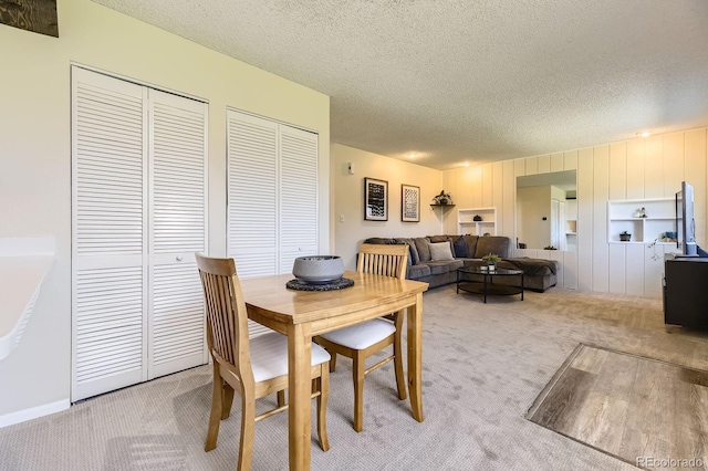 carpeted dining space featuring a textured ceiling
