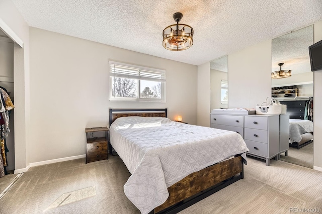 bedroom with a chandelier, a textured ceiling, light colored carpet, and baseboards