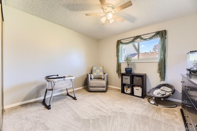 living area featuring a textured ceiling, ceiling fan, baseboards, and carpet