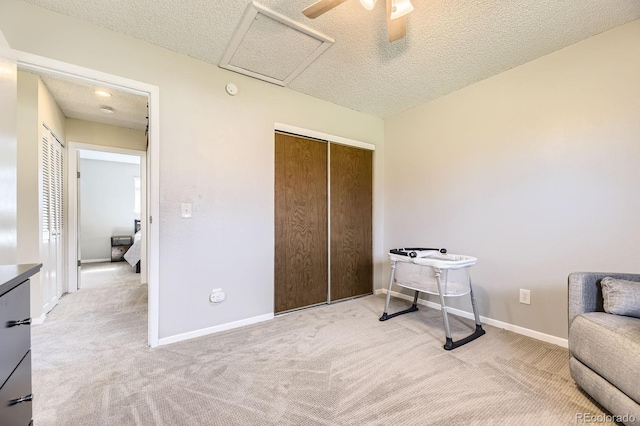 living area with baseboards, attic access, light carpet, and a textured ceiling