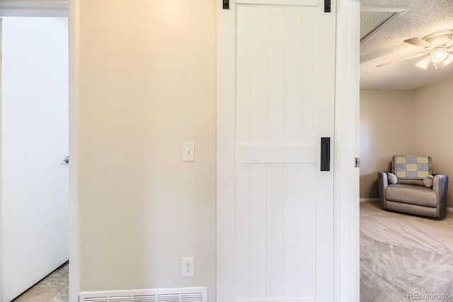 bedroom featuring a textured ceiling, a barn door, visible vents, ceiling fan, and light colored carpet