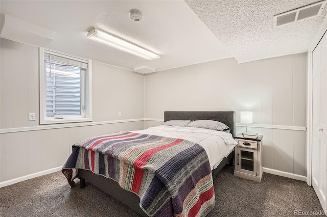 bedroom featuring dark colored carpet, visible vents, and a textured ceiling