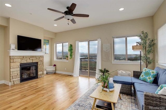 living room with light hardwood / wood-style flooring, ceiling fan, and a fireplace