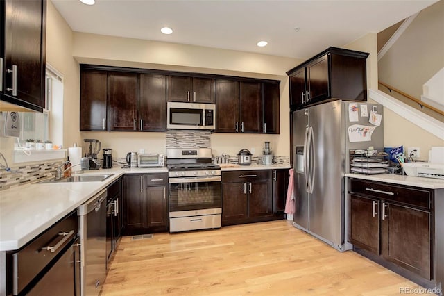 kitchen featuring dark brown cabinetry, light hardwood / wood-style floors, stainless steel appliances, and tasteful backsplash