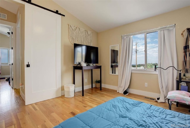 bedroom with lofted ceiling, hardwood / wood-style floors, and a barn door