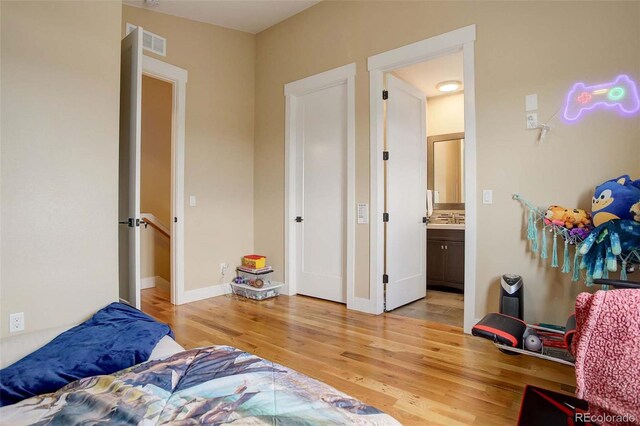 bedroom featuring light hardwood / wood-style flooring and ensuite bathroom