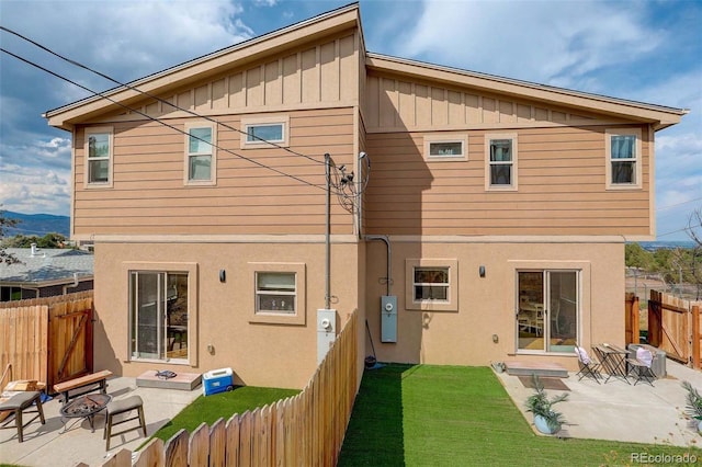 back of house with a lawn, a patio area, and a fire pit