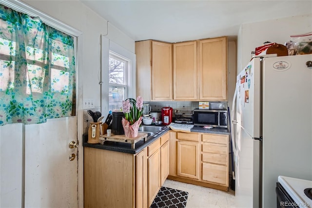 kitchen featuring light brown cabinets, white appliances, and tasteful backsplash