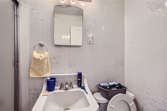 bathroom with sink, toilet, and tile walls