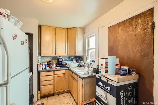kitchen with white refrigerator, light tile patterned floors, sink, and light brown cabinetry