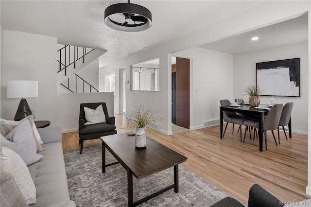 9338 W Utah Pl, Lakewood, CO 80232 - living area with ceiling fan, stairway, light wood-type flooring, baseboards, and a textured ceiling
