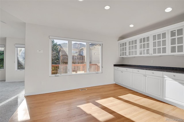 kitchen featuring visible vents, dark countertops, glass insert cabinets, white cabinetry, and recessed lighting