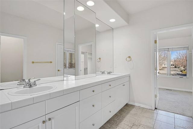 full bath featuring recessed lighting, a sink, baseboards, and double vanity