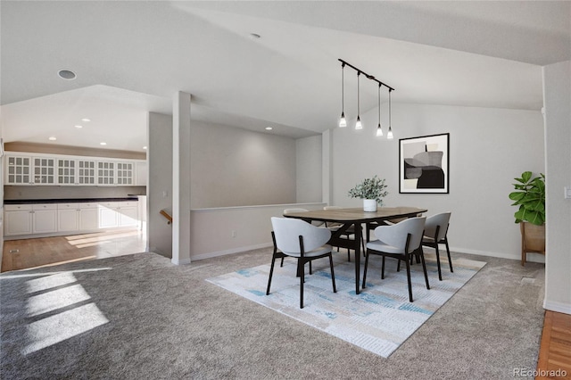 dining room featuring vaulted ceiling and light carpet