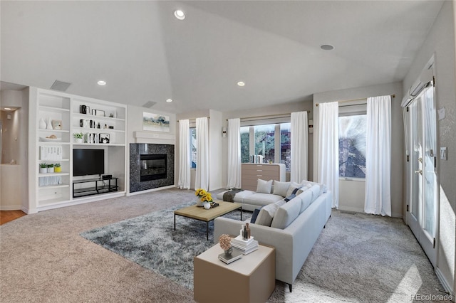 living room with lofted ceiling, light carpet, and a high end fireplace