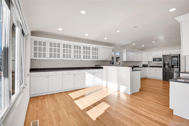 kitchen featuring visible vents, appliances with stainless steel finishes, light wood-style floors, glass insert cabinets, and white cabinets