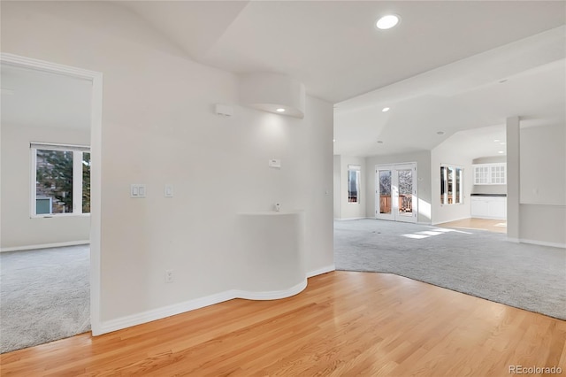 spare room featuring recessed lighting, light carpet, light wood finished floors, and baseboards