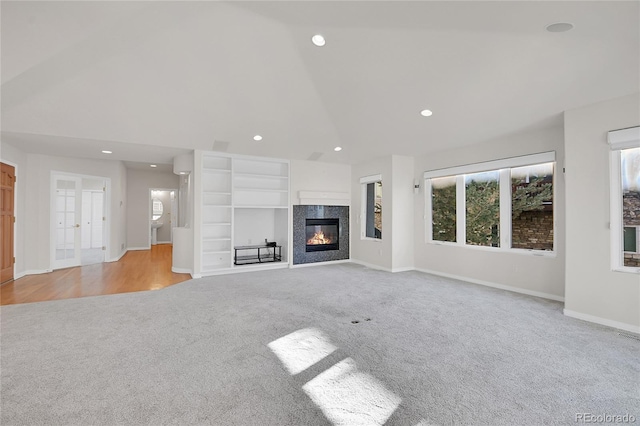 unfurnished living room featuring carpet floors, a fireplace, recessed lighting, high vaulted ceiling, and baseboards