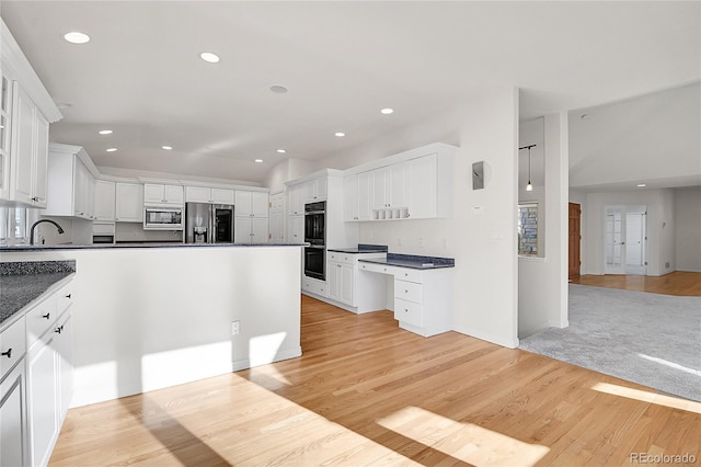 kitchen with light wood finished floors, white cabinets, dark countertops, appliances with stainless steel finishes, and recessed lighting