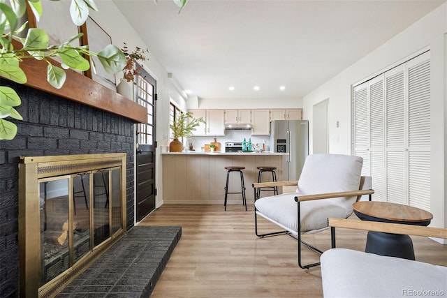 living room featuring a fireplace, recessed lighting, and light wood-type flooring