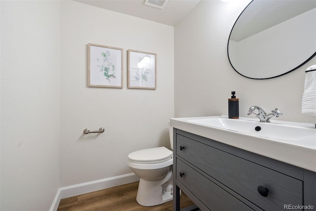 half bath featuring vanity, toilet, baseboards, visible vents, and wood finished floors