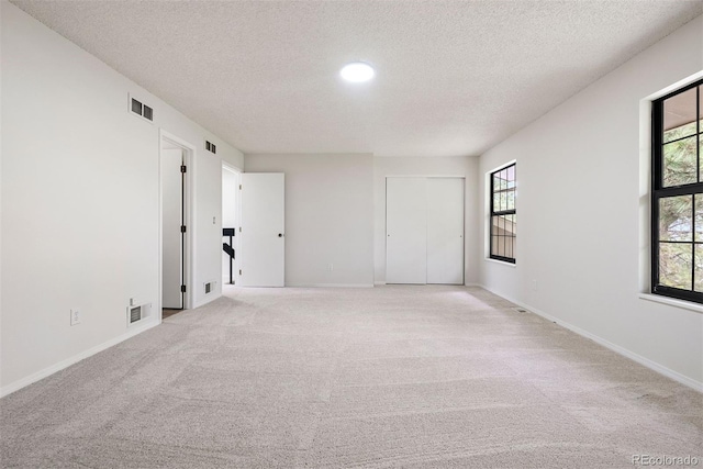 unfurnished room featuring baseboards, visible vents, and light carpet