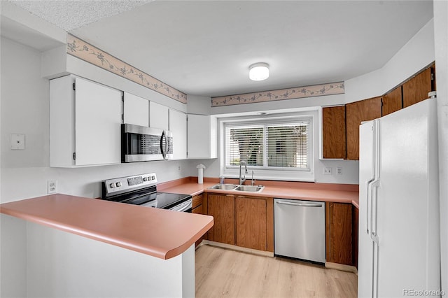 10143 Quivas St, Thornton, CO 80260 - kitchen with stainless steel appliances, light wood-style floors, light countertops, a peninsula, and white cabinets