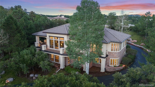 back house at dusk featuring a balcony