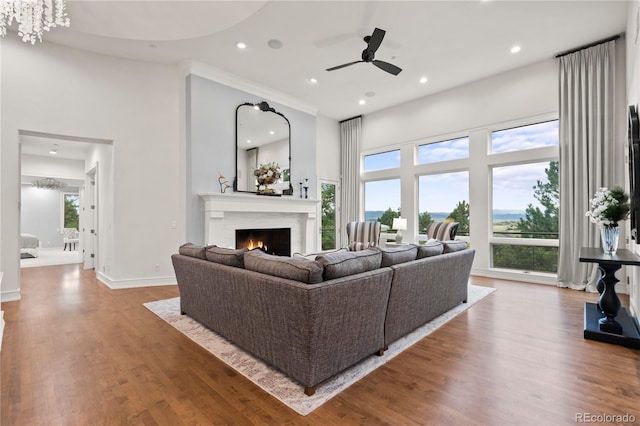 living room with hardwood / wood-style floors, ceiling fan, and a high ceiling