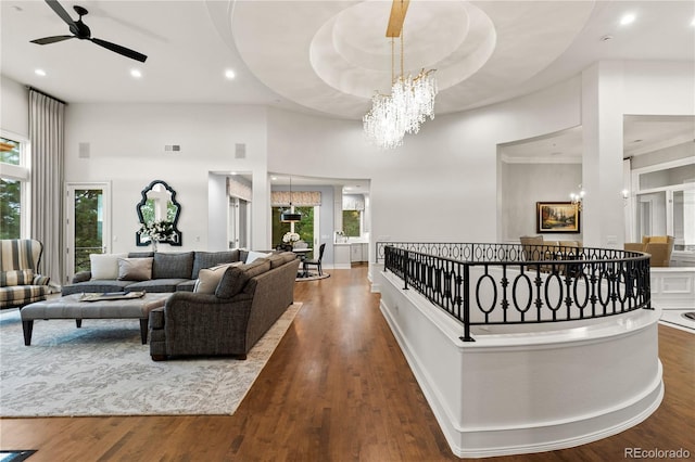 interior space with ceiling fan with notable chandelier, a wealth of natural light, a towering ceiling, and dark hardwood / wood-style flooring