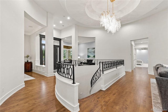 hallway featuring a tray ceiling, hardwood / wood-style floors, and an inviting chandelier