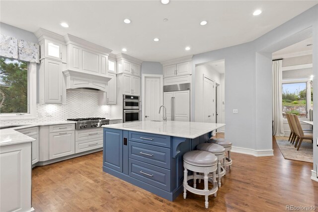 kitchen with tasteful backsplash, a center island with sink, light hardwood / wood-style flooring, and appliances with stainless steel finishes