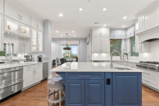 kitchen with an island with sink, wood-type flooring, stainless steel gas cooktop, white cabinetry, and sink