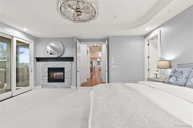 carpeted bedroom featuring a stone fireplace and access to outside