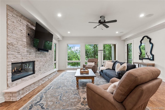 living room featuring a fireplace, ceiling fan, and light wood-type flooring