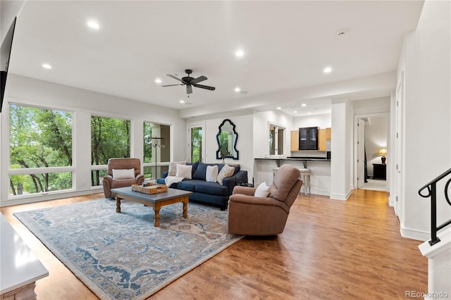 living room featuring ceiling fan, plenty of natural light, and light hardwood / wood-style floors