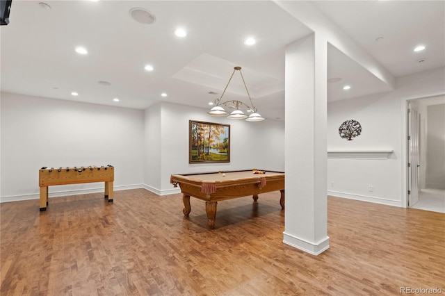 recreation room featuring billiards, light hardwood / wood-style floors, and a raised ceiling