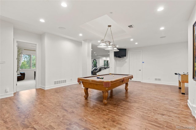 rec room with pool table, a tray ceiling, and light wood-type flooring