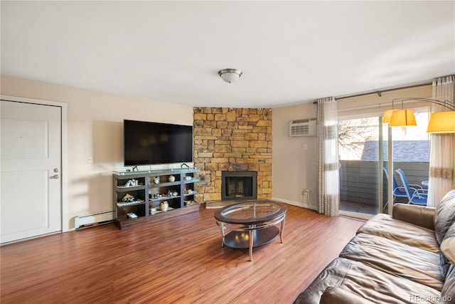 living room featuring hardwood / wood-style floors, a stone fireplace, an AC wall unit, and baseboard heating