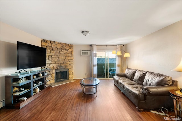 living room with a fireplace, hardwood / wood-style floors, and a wall unit AC