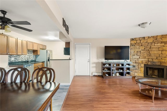 interior space with sink, ceiling fan, hardwood / wood-style floors, a fireplace, and a baseboard radiator