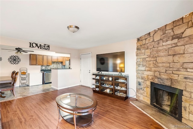 living room with ceiling fan, a fireplace, and light hardwood / wood-style floors