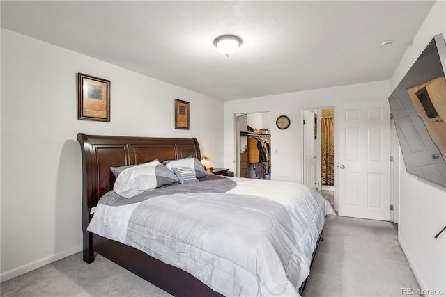 bedroom featuring light colored carpet, a closet, and a walk in closet