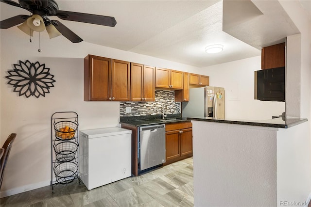 kitchen featuring sink, ceiling fan, stainless steel appliances, decorative backsplash, and kitchen peninsula